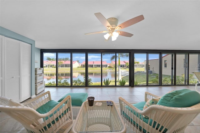 sunroom / solarium featuring ceiling fan and a water view