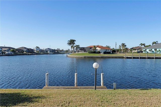 view of dock with a lawn and a water view