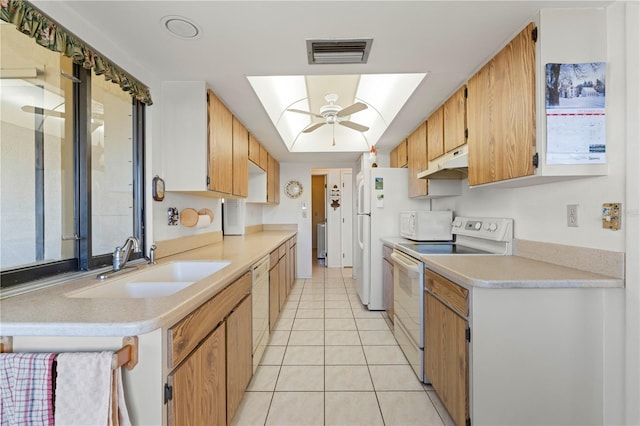 kitchen featuring light tile patterned flooring, a skylight, sink, ceiling fan, and white appliances