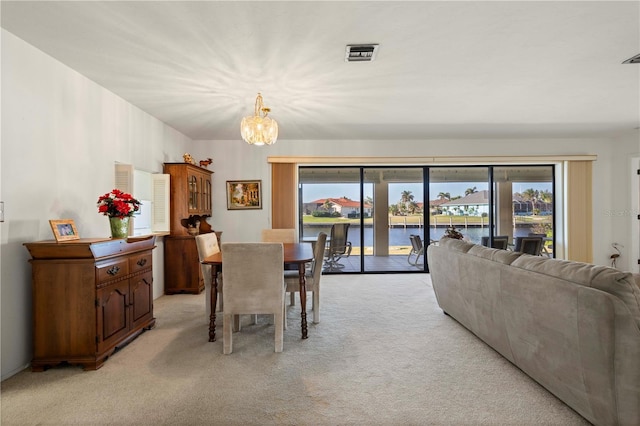 carpeted dining area featuring a water view and a notable chandelier