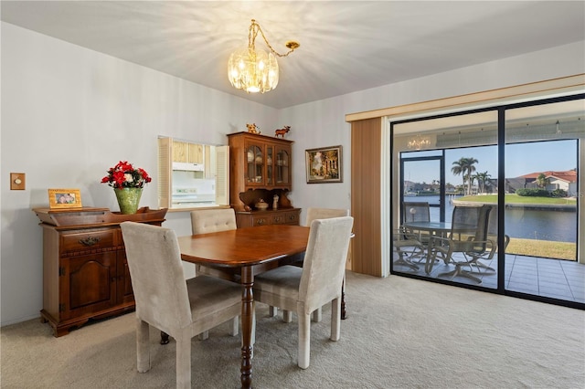 carpeted dining space featuring a water view and an inviting chandelier