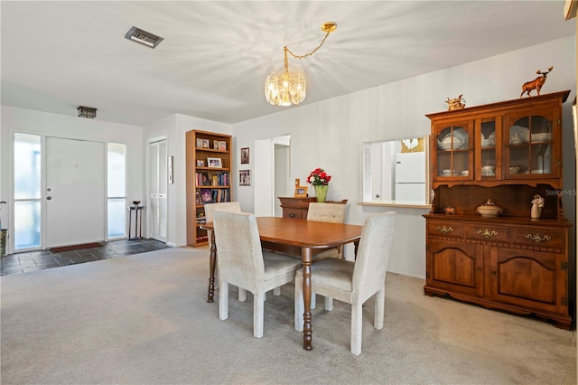 dining space with light colored carpet and an inviting chandelier