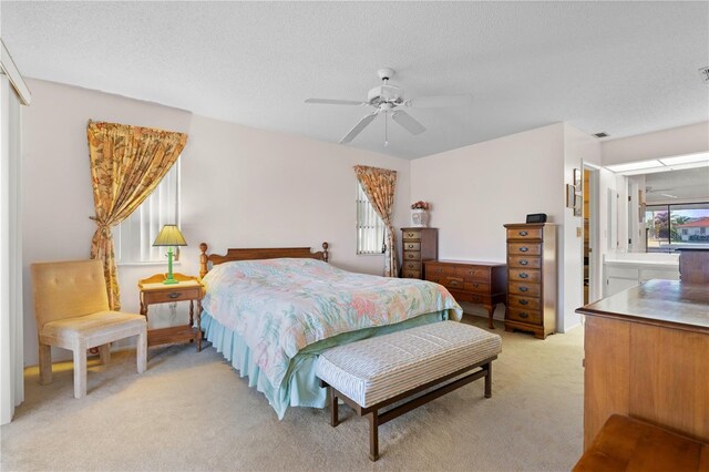 bedroom featuring ceiling fan, light colored carpet, and a textured ceiling