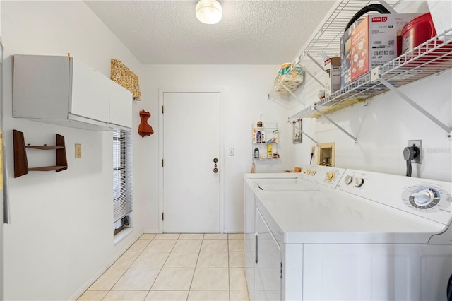 clothes washing area with cabinets, independent washer and dryer, a textured ceiling, and light tile patterned flooring