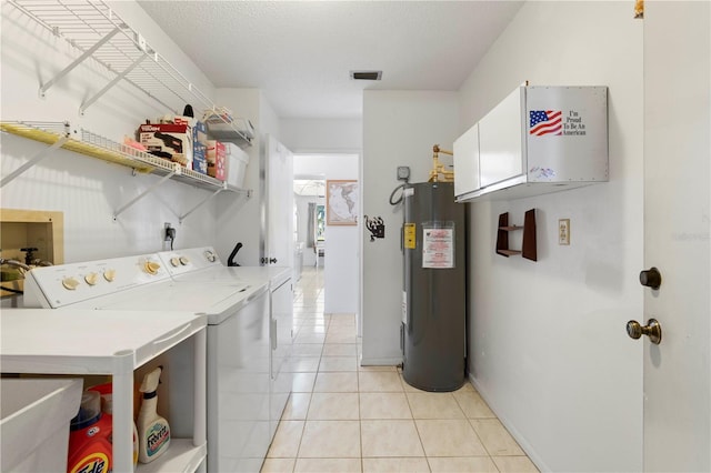 laundry room with light tile patterned floors, cabinets, electric water heater, a textured ceiling, and washing machine and clothes dryer