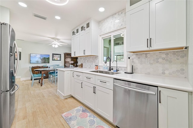 kitchen with sink, tasteful backsplash, light hardwood / wood-style flooring, stainless steel appliances, and white cabinets