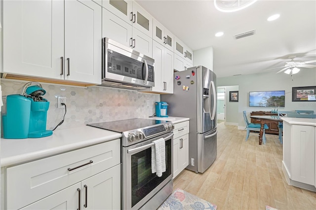 kitchen with backsplash, stainless steel appliances, light hardwood / wood-style floors, and white cabinets