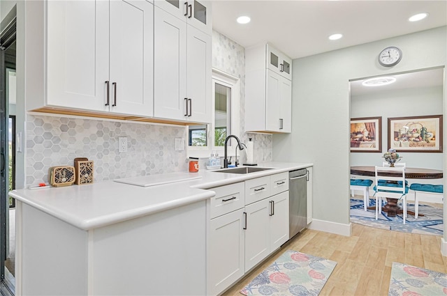 kitchen featuring dishwasher, white cabinetry, sink, decorative backsplash, and light hardwood / wood-style flooring