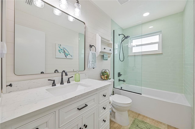 full bathroom featuring vanity, hardwood / wood-style flooring, toilet, and combined bath / shower with glass door