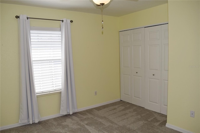 unfurnished bedroom with light colored carpet and a closet