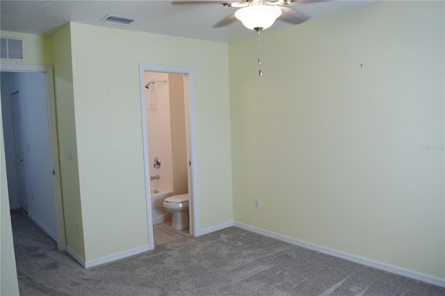 unfurnished bedroom with connected bathroom, light colored carpet, and ceiling fan