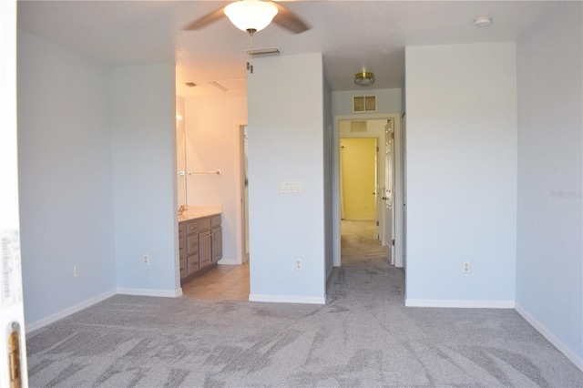 unfurnished bedroom featuring ceiling fan, light colored carpet, and ensuite bathroom