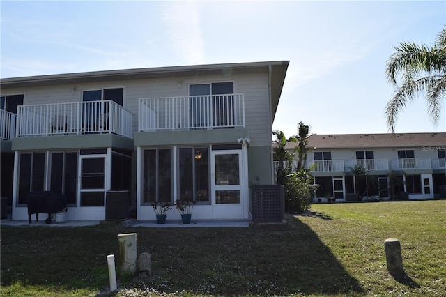 back of house featuring a lawn, a sunroom, and a balcony