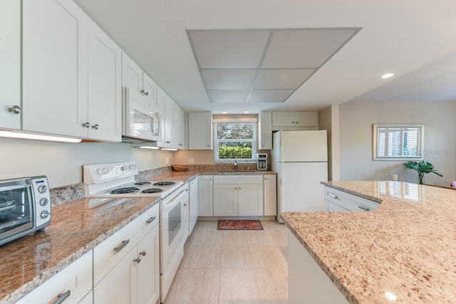 kitchen featuring white appliances, light stone countertops, sink, and white cabinets