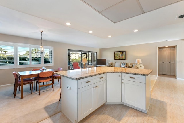 kitchen with white cabinetry, a center island, pendant lighting, and light stone counters