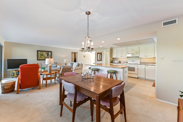 dining area with light carpet and a notable chandelier