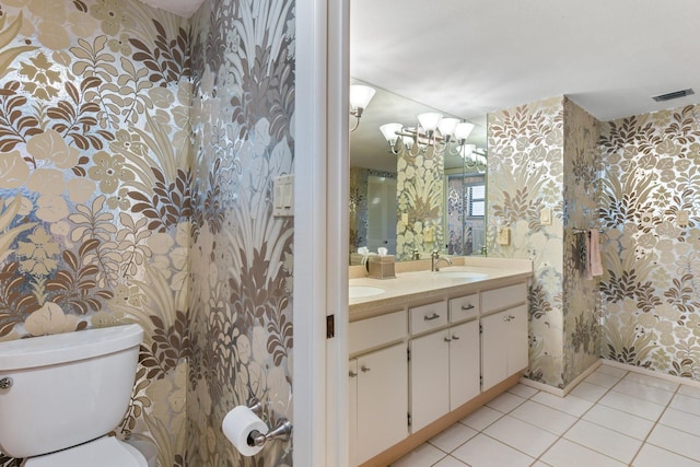 bathroom featuring tile patterned flooring, vanity, a notable chandelier, and toilet