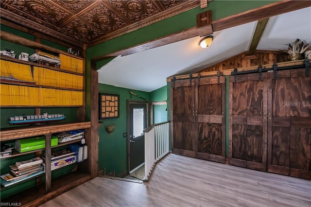 entryway featuring a barn door, light wood-type flooring, and vaulted ceiling with beams