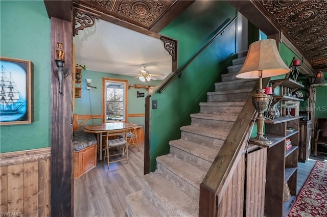 stairway featuring ceiling fan, hardwood / wood-style floors, and a textured ceiling