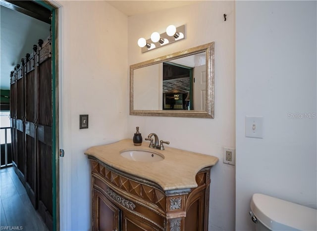 bathroom featuring vanity, hardwood / wood-style floors, and toilet