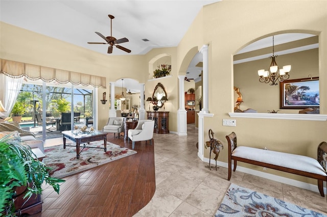 living room with decorative columns, ceiling fan with notable chandelier, high vaulted ceiling, and light hardwood / wood-style floors