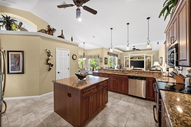 kitchen with stone counters, a kitchen island, appliances with stainless steel finishes, pendant lighting, and sink