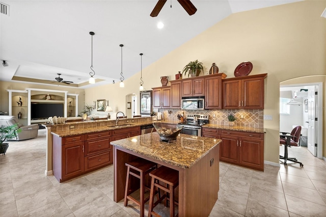 kitchen featuring sink, hanging light fixtures, stainless steel appliances, a kitchen breakfast bar, and a kitchen island