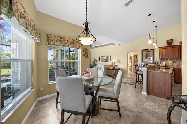 tiled dining area with vaulted ceiling and sink