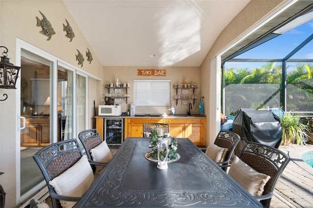 dining area with lofted ceiling, sink, and beverage cooler