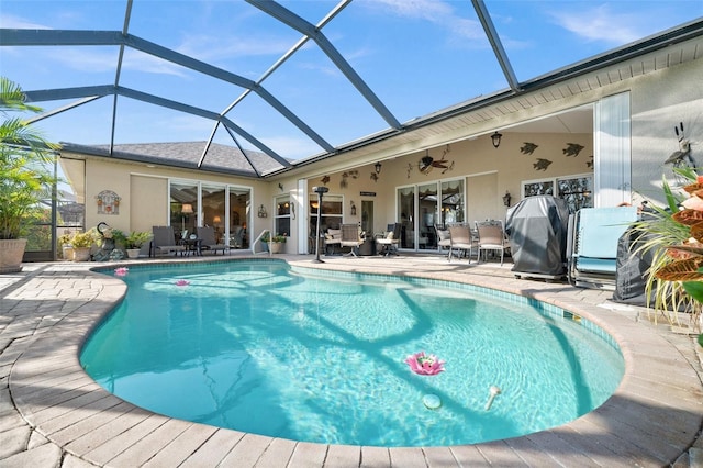 view of pool featuring area for grilling, a patio, ceiling fan, and glass enclosure