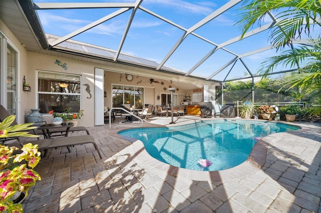 view of swimming pool with ceiling fan, glass enclosure, a patio area, and a hot tub