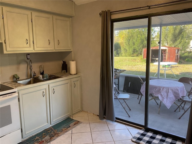 12077 Maryland Ave, Punta Gorda, FL 33955 - kitchen with light tile patterned flooring, sink, white cabinetry, electric range, and decorative backsplash