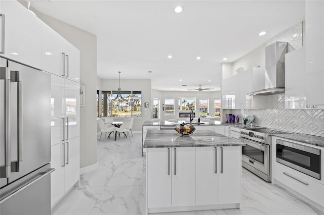 3415 Tripoli Blvd, Punta Gorda, FL 33950 - kitchen with white cabinets, wall chimney range hood, high quality appliances, and a center island