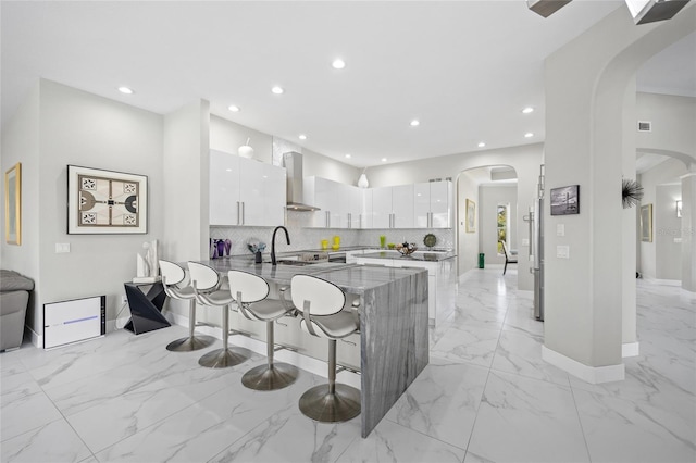 3415 Tripoli Blvd, Punta Gorda, FL 33950 - kitchen with a kitchen breakfast bar, kitchen peninsula, white cabinetry, and wall chimney range hood