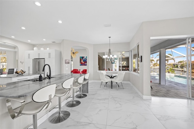 3415 Tripoli Blvd, Punta Gorda, FL 33950 - kitchen featuring an inviting chandelier, light stone countertops, white cabinets, hanging light fixtures, and high end refrigerator
