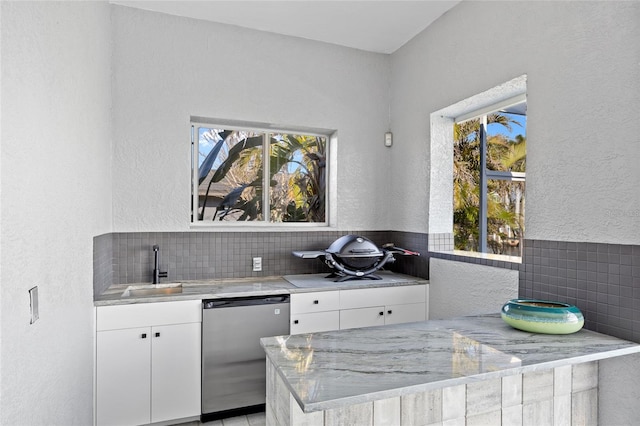 3415 Tripoli Blvd, Punta Gorda, FL 33950 - kitchen with light stone counters, dishwashing machine, backsplash, sink, and white cabinetry