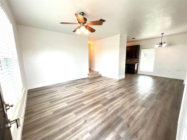 unfurnished living room with hardwood / wood-style flooring and ceiling fan with notable chandelier