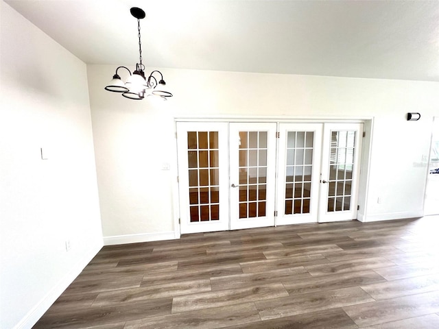 unfurnished dining area with dark wood-type flooring, a notable chandelier, and french doors