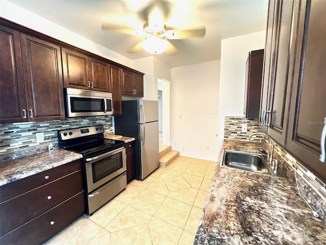 kitchen featuring appliances with stainless steel finishes, tasteful backsplash, sink, dark stone counters, and light tile patterned floors