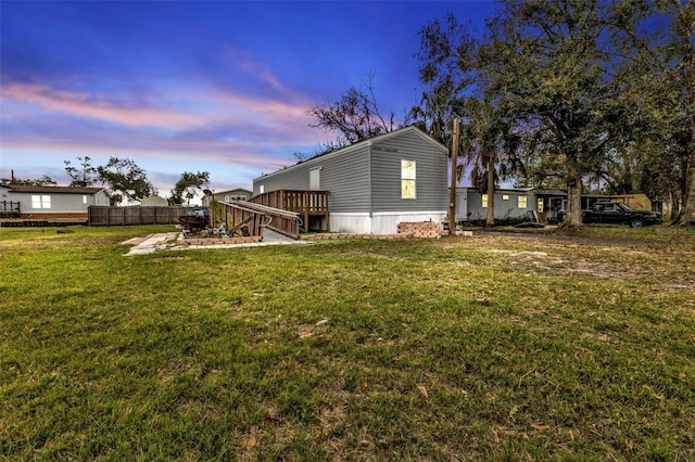 property exterior at dusk featuring a deck and a lawn