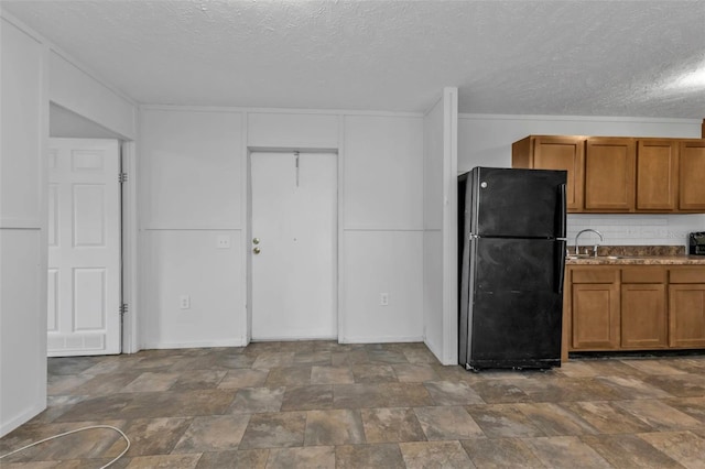 kitchen with black fridge, sink, and a textured ceiling