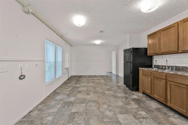 kitchen with black refrigerator, sink, decorative backsplash, and a textured ceiling