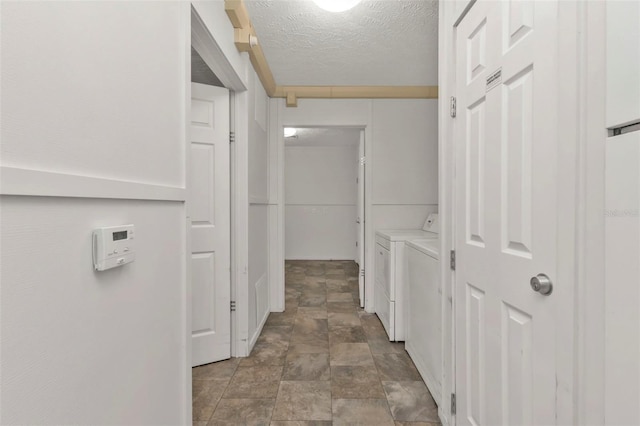 hallway with a textured ceiling and independent washer and dryer