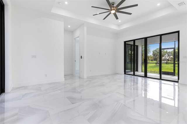 empty room featuring a raised ceiling and ceiling fan