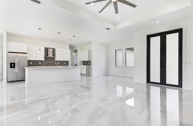 unfurnished living room featuring french doors, ceiling fan, and a tray ceiling