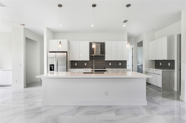 kitchen featuring white cabinetry, stainless steel refrigerator with ice dispenser, an island with sink, and wall chimney exhaust hood