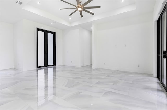 empty room featuring a raised ceiling, ceiling fan, and french doors