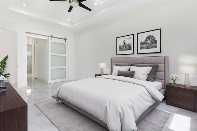 bedroom with a barn door, ceiling fan, and a tray ceiling