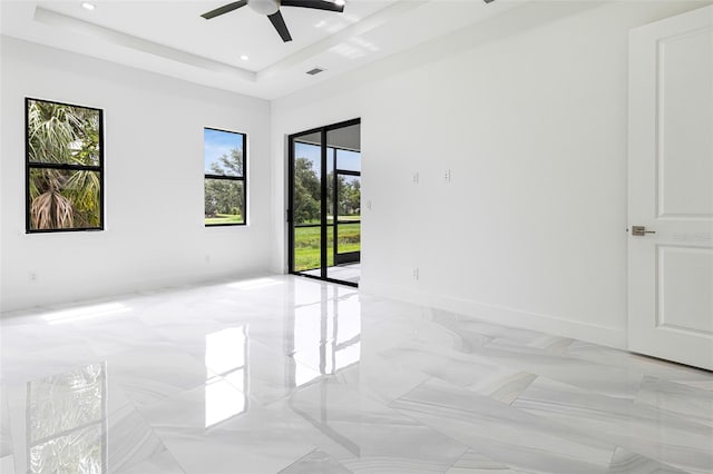 empty room with a raised ceiling and ceiling fan