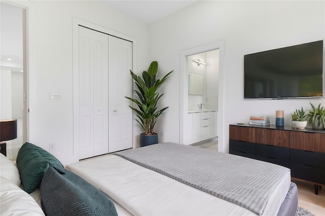 bedroom with light hardwood / wood-style flooring, sink, connected bathroom, and a closet